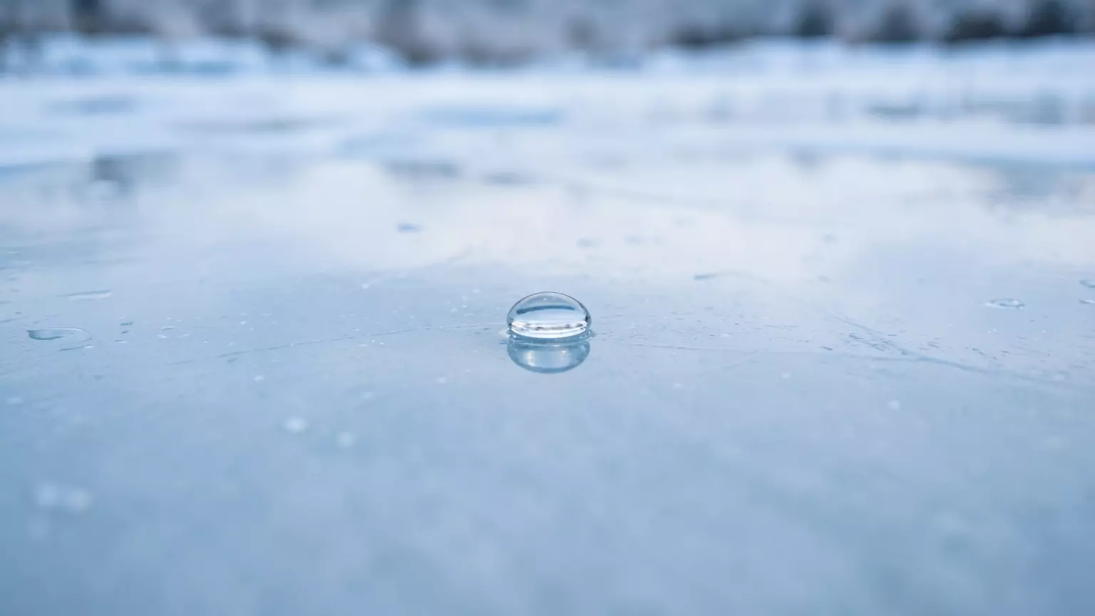 Гладкая поверхность льда с небольшой прозрачной каплей воды